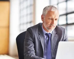 Imagem de homem em ambiente de escritório usando laptop.